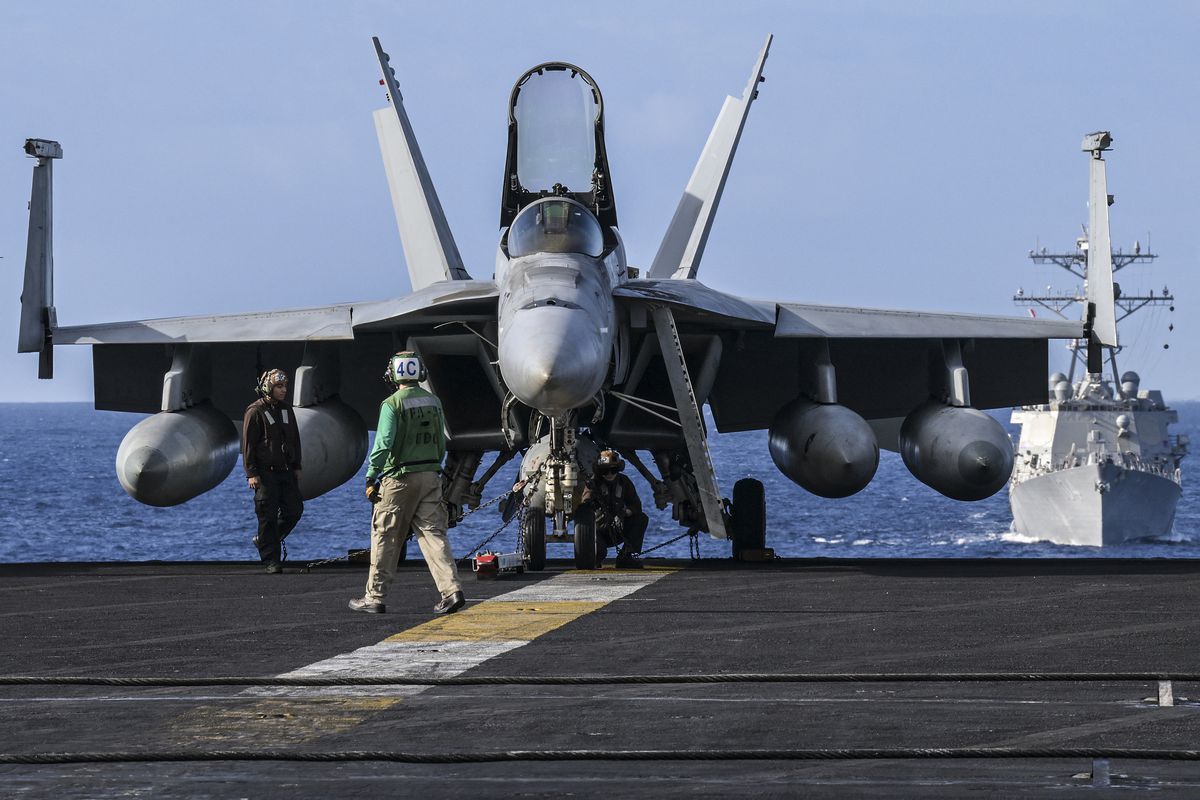 Crew members stand by an F/A-18 on the flight deck onboard the USS Carl Vinson aircraft carrier during a three-day maritime exercise between the US and Japan in the Philippine Sea on January 31, 2024.