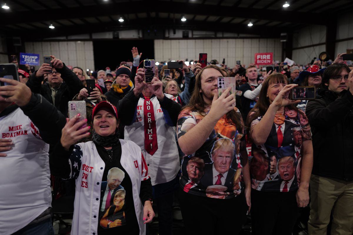 A crowd of people in Trump merch, many of whom are holding up smartphones to film.