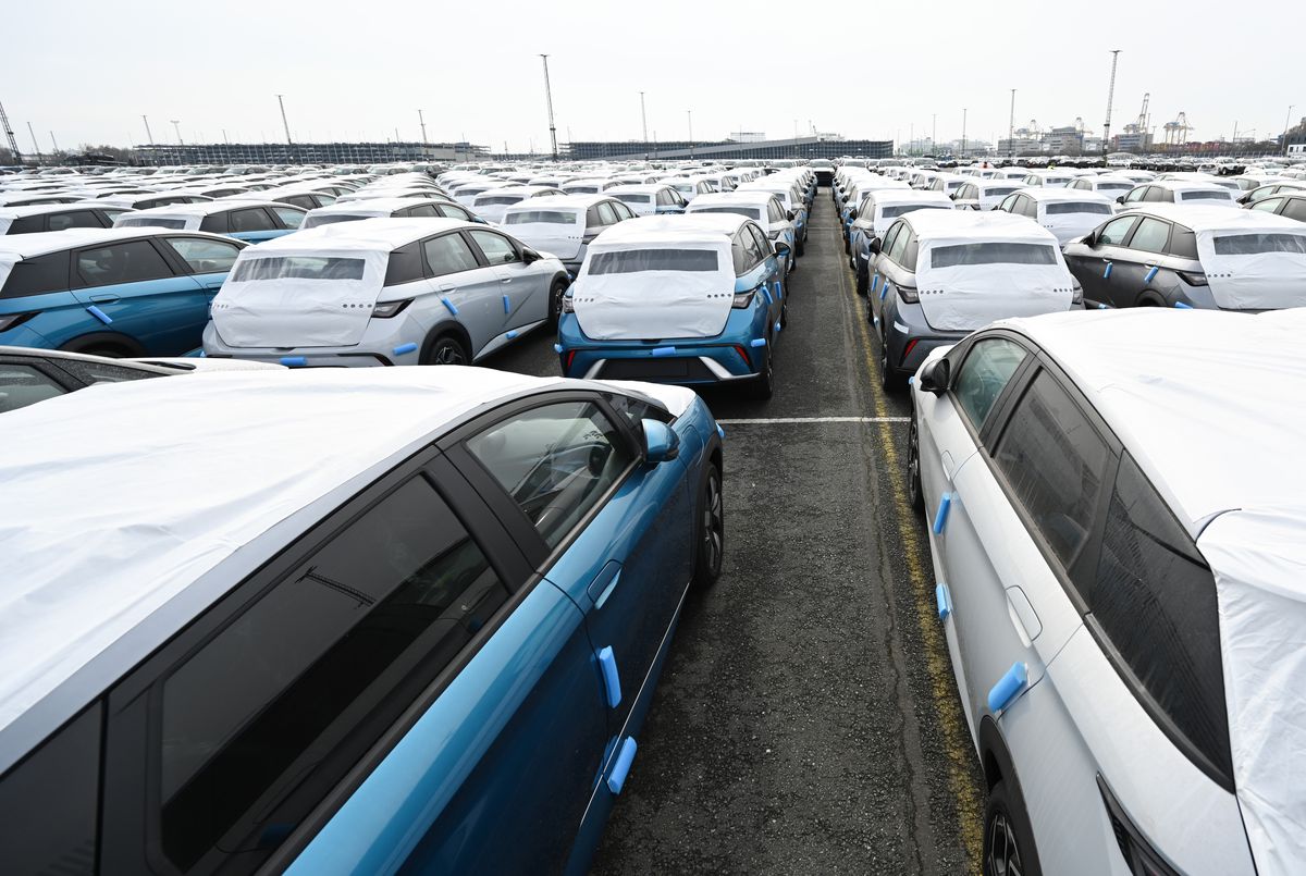 A parking lot filled with rows of blue and white cars.