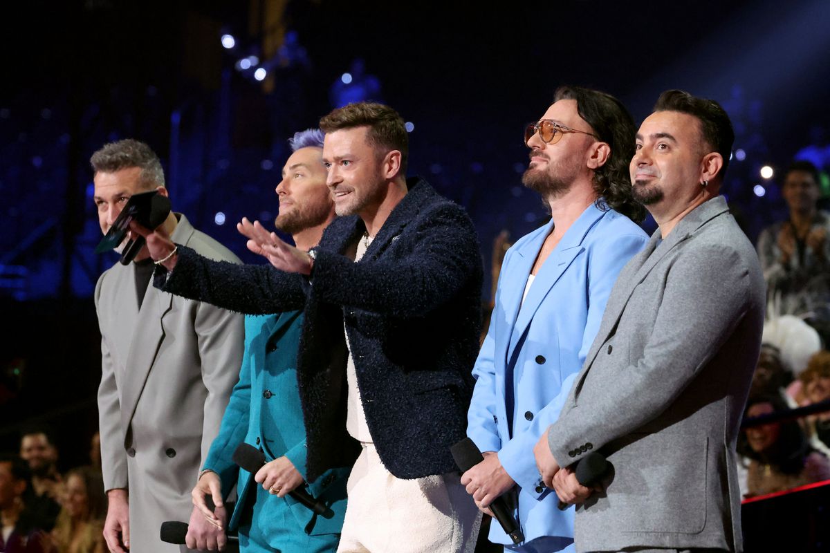 Timberlake gestures to the audience while the other members of the band stand by.