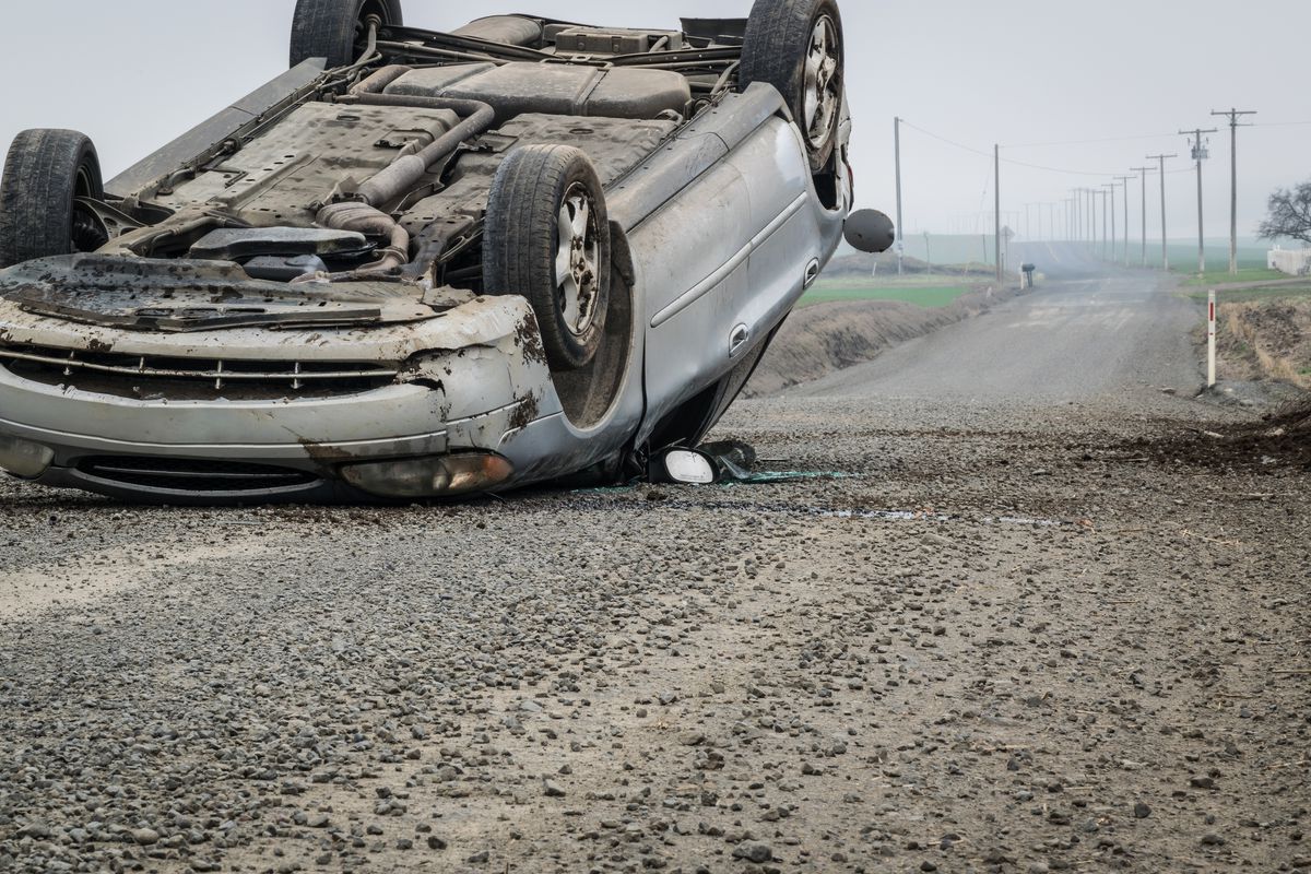 Photo of an overturned car after a crash on a rural road.