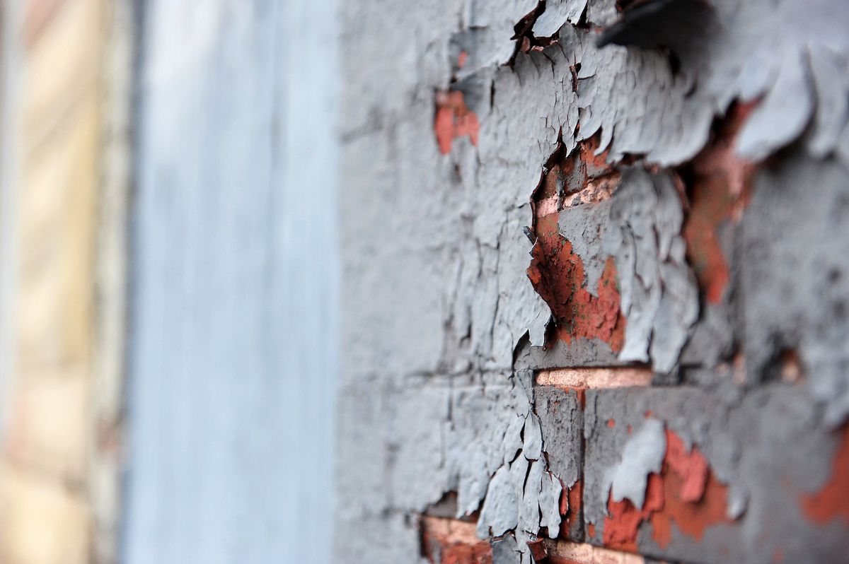 Peeling lead paint on the brick wall of a home.