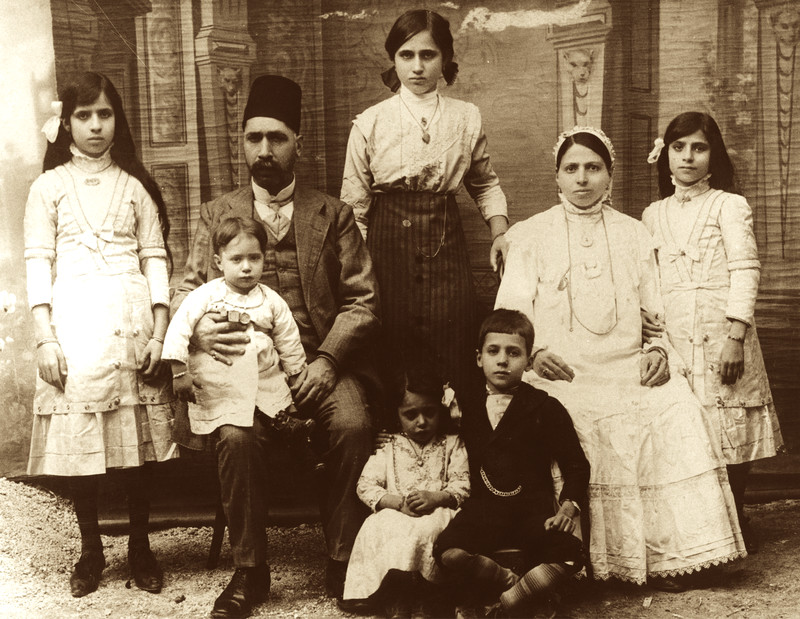 A sepia-toned Mizrahi family portrait showing what appears to be a father, mother, and six children.