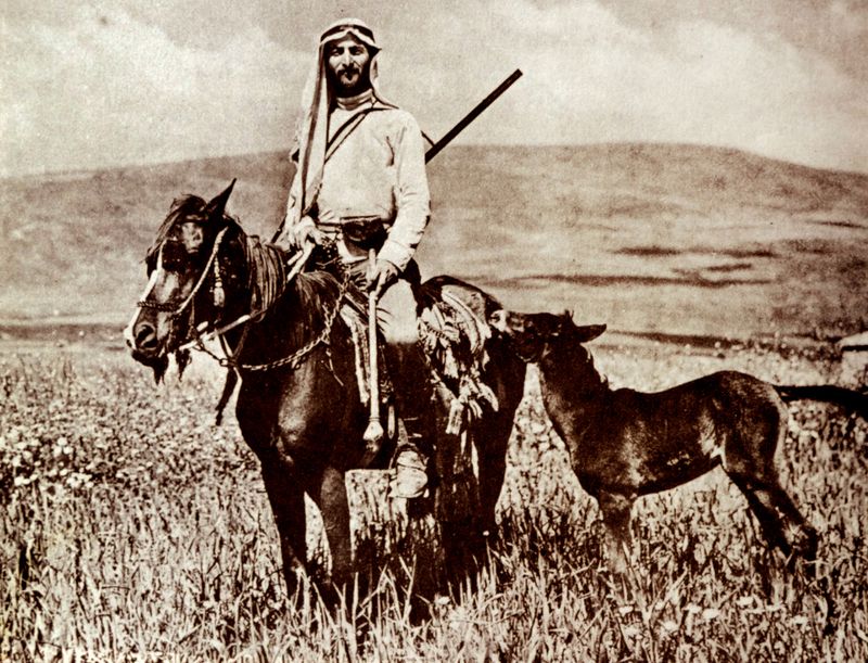 Sepia-toned photo of a guard on horseback, appearing to wear traditional Bedouin clothing
