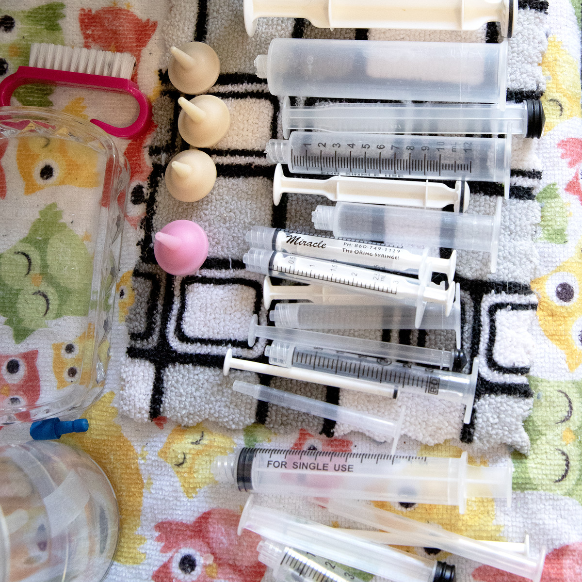 Plastic syringes laid out on a blanket.