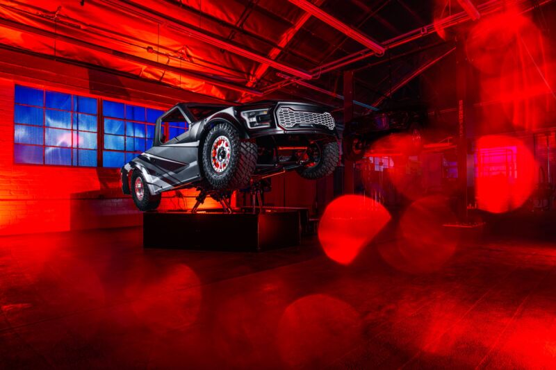 A stylized photo of the CXC off-road simulator, with lots of red lens flare partially obscuring it.