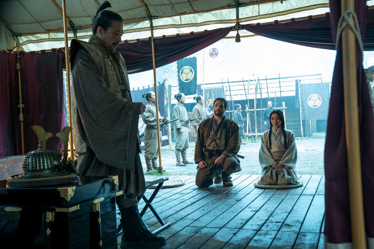 A white man and Japanese woman kneel before a Japanese man.