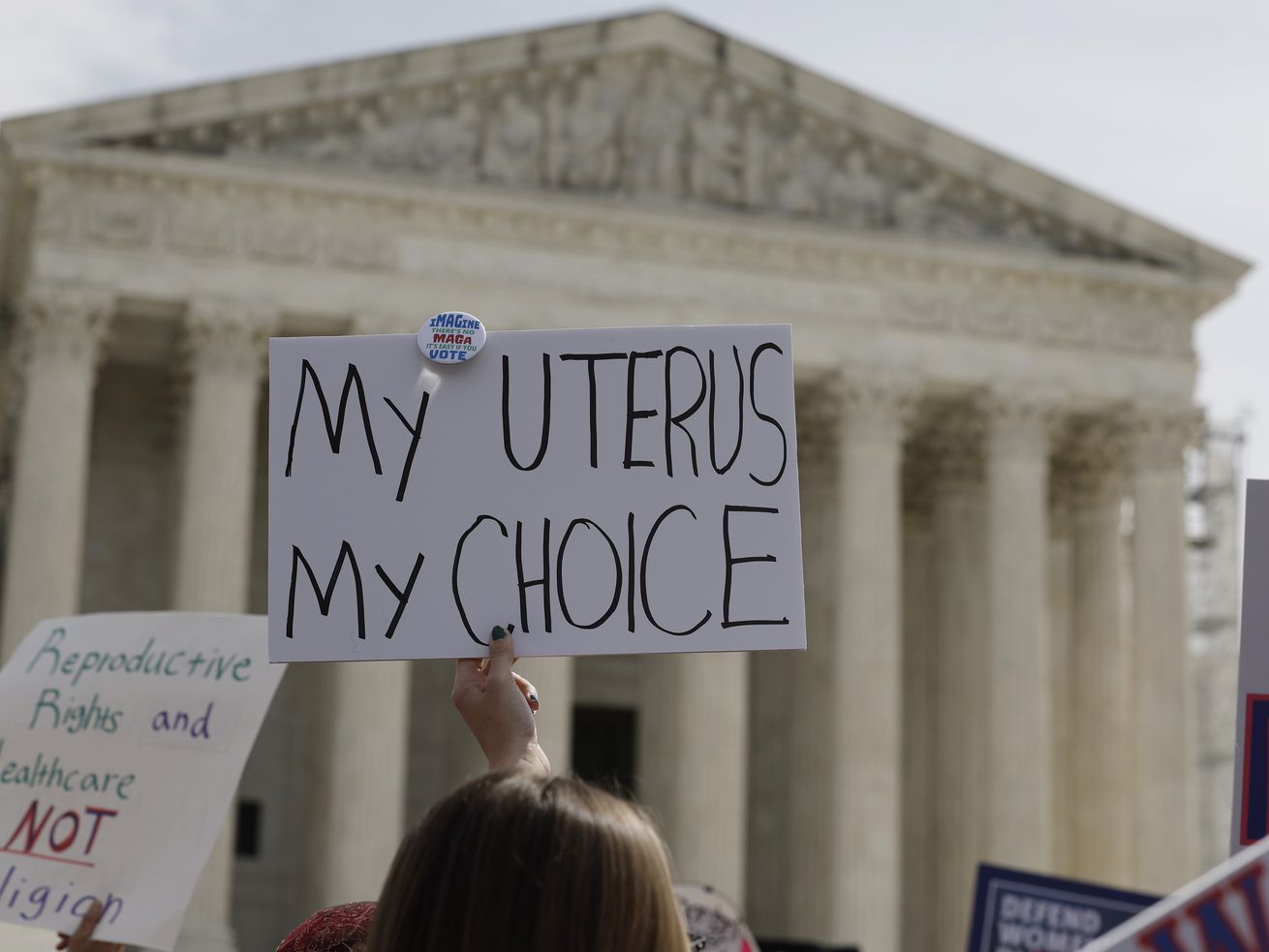 A sign is raised outside the Supreme Court building that says “My uterus my choice.”