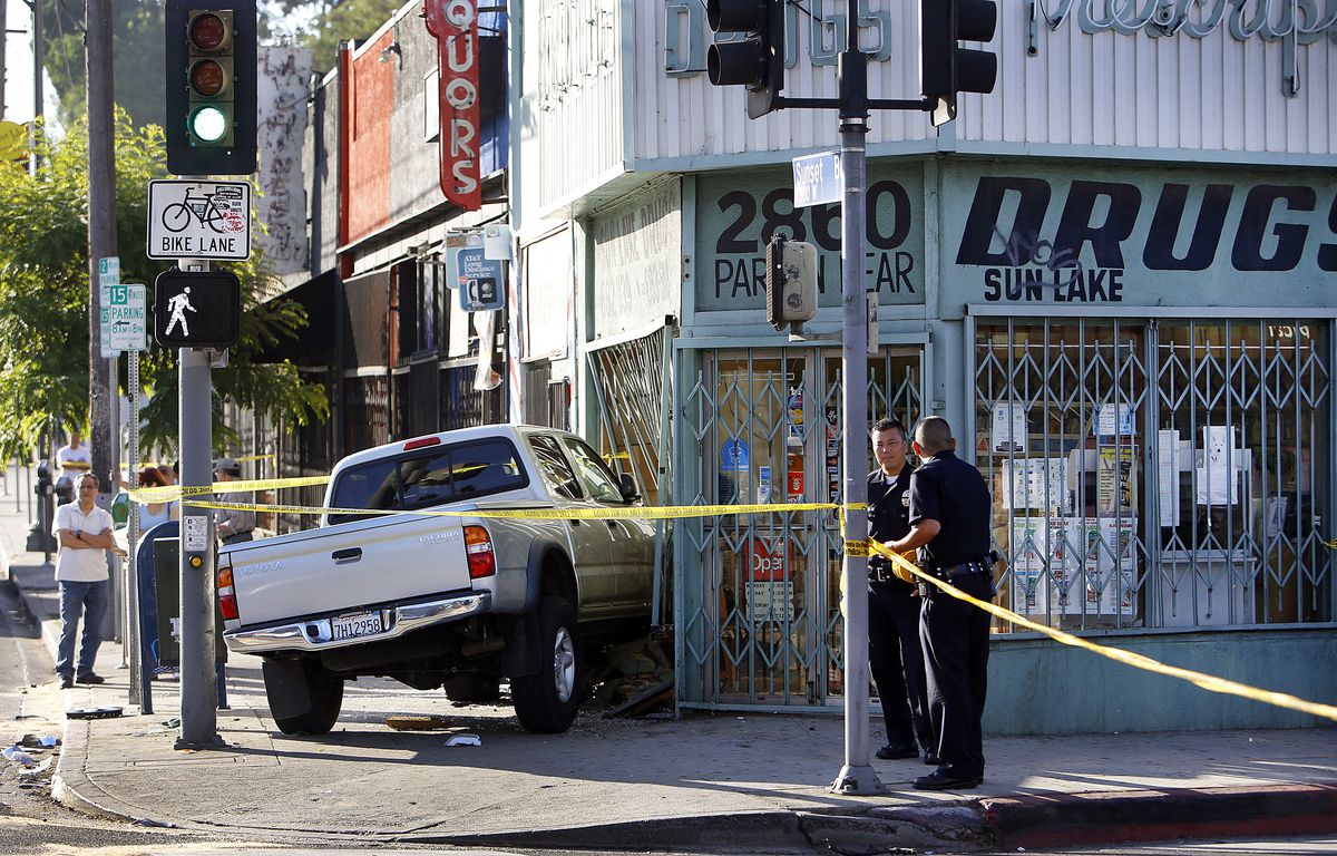 A pickup truck crashed into a storefront is cordoned off by police.
