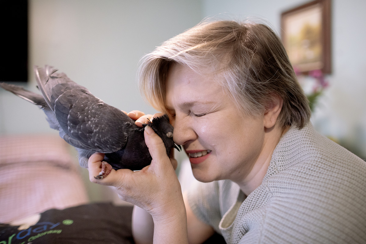 Martin holds a pigeon up to her face in her apartment.