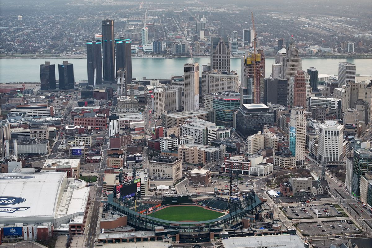 An aerial view of a baseball stadium and surrounding urban buildings and high-rises, with a lake visible in the background.