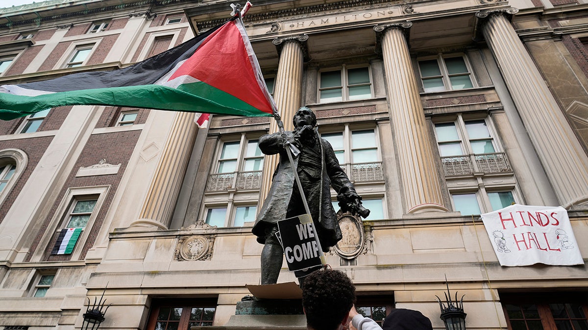 A student protester parades a Palestinian flag outside the entrance to Hamilton Hall on the campus of Columbia University