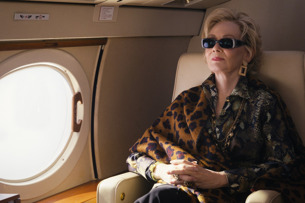 Deborah smiling in sunglasses on her private jet.