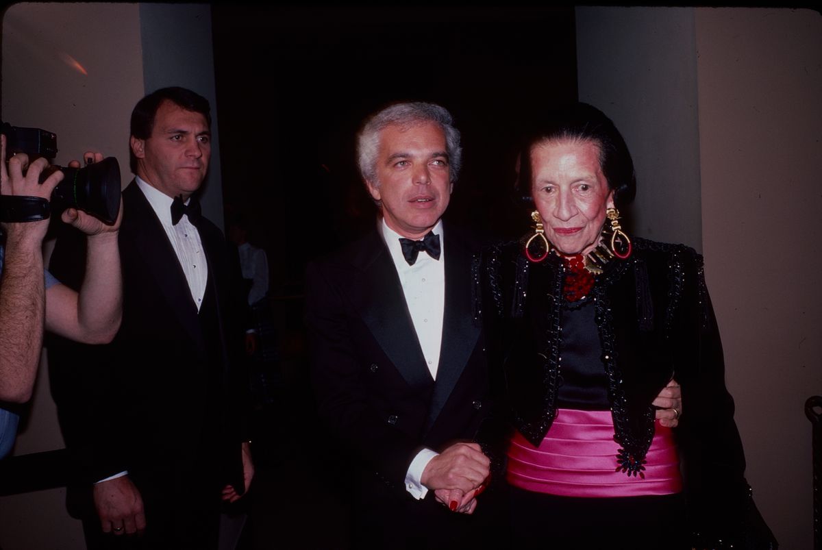 A dark photograph from 1984 shows Ralph Lauren in a suit with a black bow tie, and Diana Vreeland in a black dress and magenta sash.
