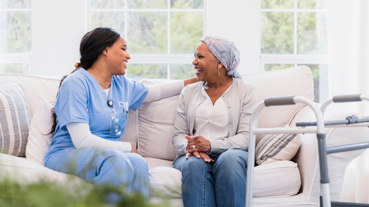 two women sitting on couch, one is a nurse