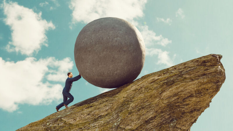 A man rolling a boulder up a hill.