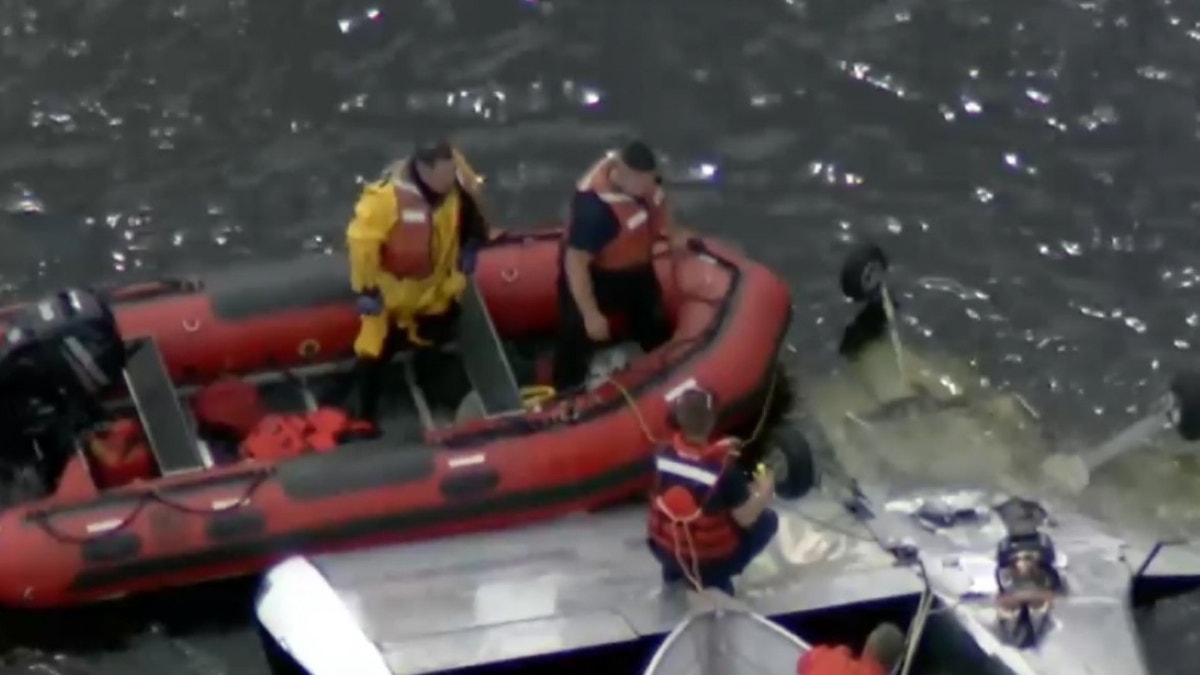 First responders in boats next to upside down plane