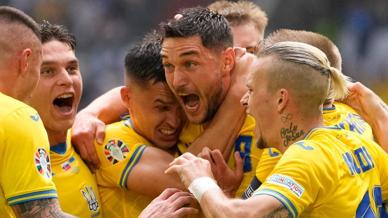 Roman Yaremchuk is mobbed by his team-mates after giving Ukraine a late lead against Slovakia