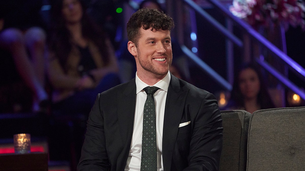 Reality star Clayton Echard smiles on the couch at The Bachelor taping