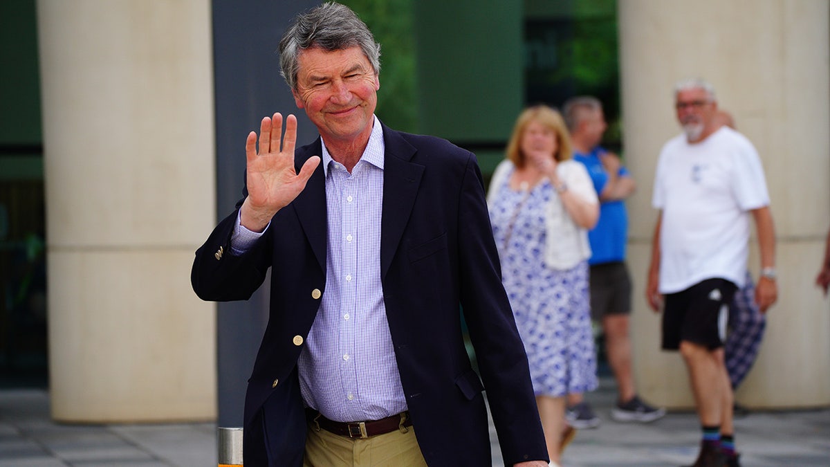 Sir Timothy Laurence smiling and waving to reporters outside the hospital