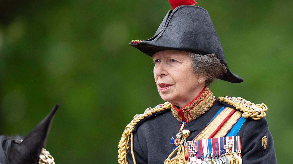 A close-up of Princess Anne in a uniform riding a horse.