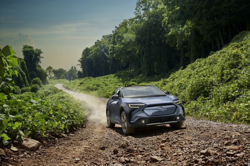 A Subaru Solterra drives on a dirt road