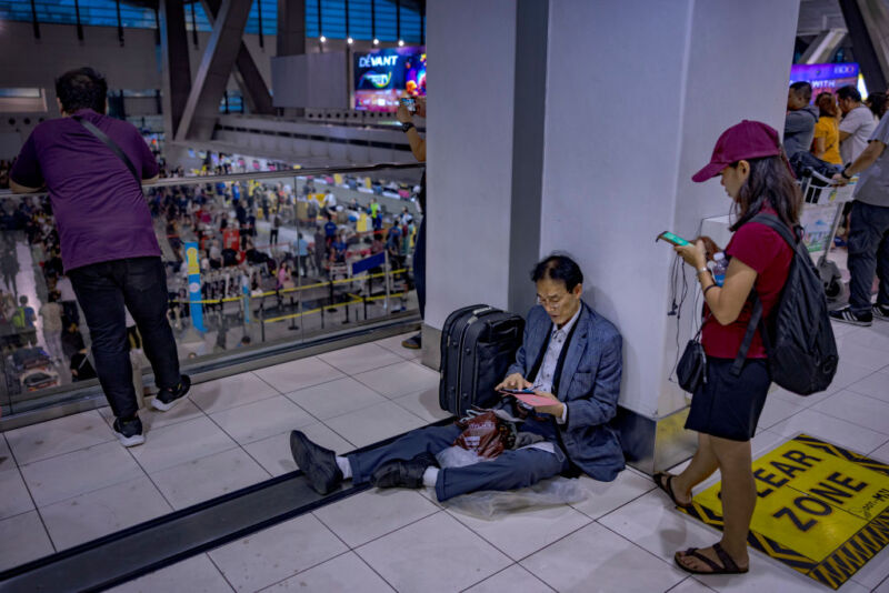 A passenger sits on the floor as long queues form at the check-in counters at Ninoy Aquino International Airport, on July 19, 2024 in Manila, Philippines.