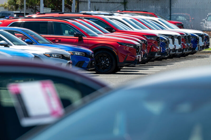 Cars lined up, shown at an angle in a row, at a car dealership.