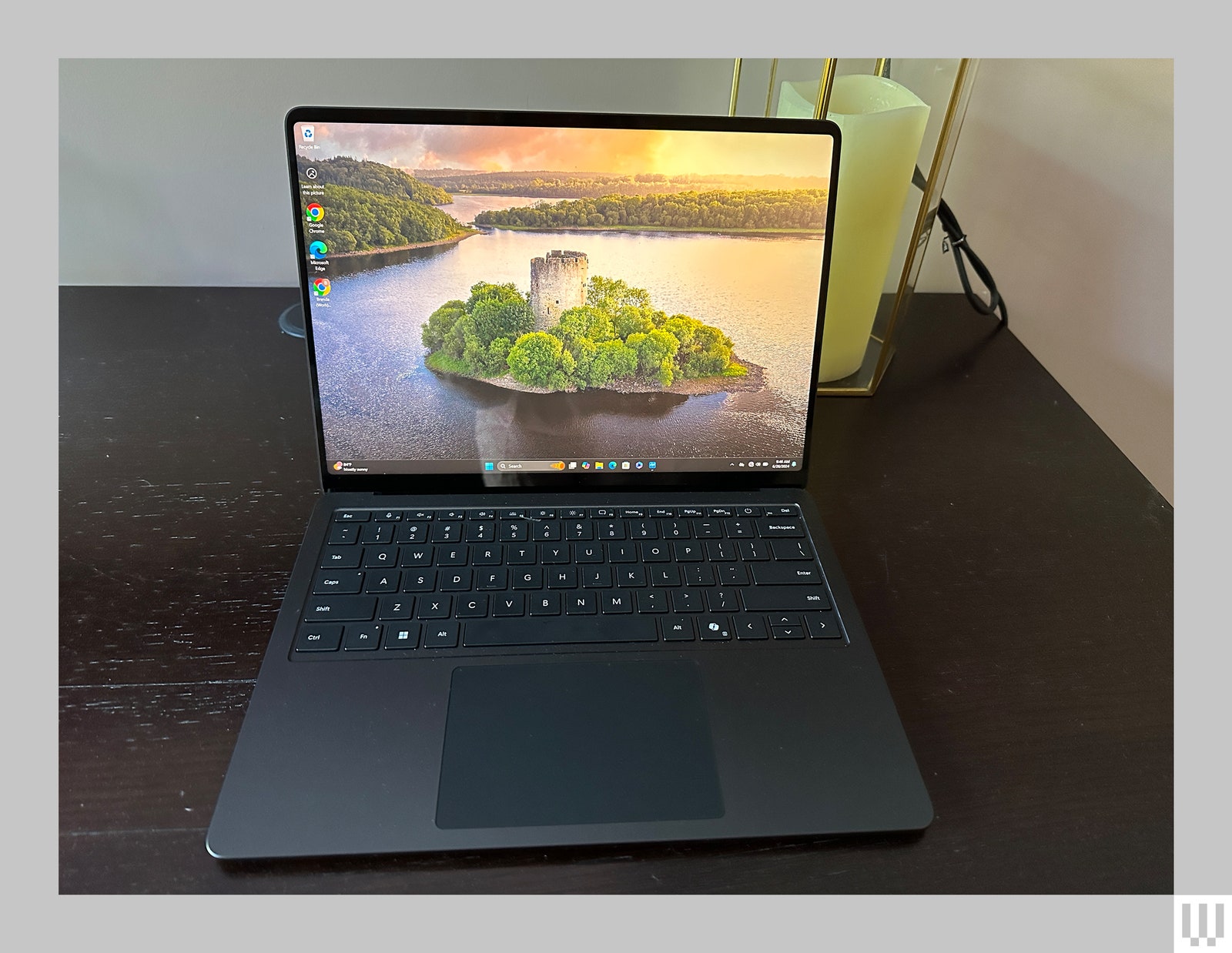 Front view of a laptop sitting on a wooden desk with the image of an island on the screen