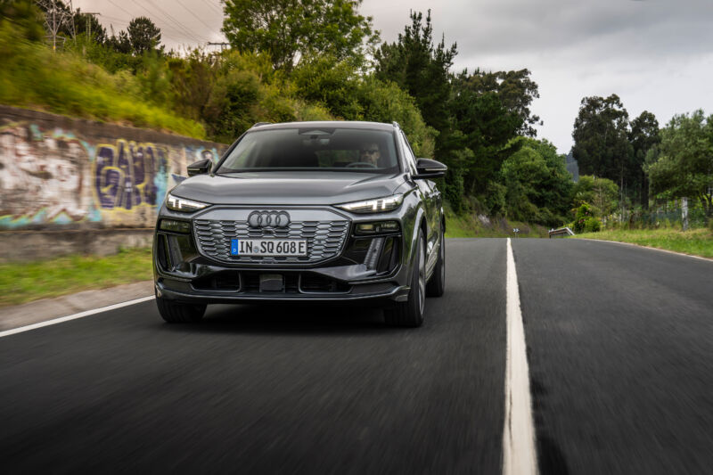 A grey Audi SQ6 drives past some graffiti