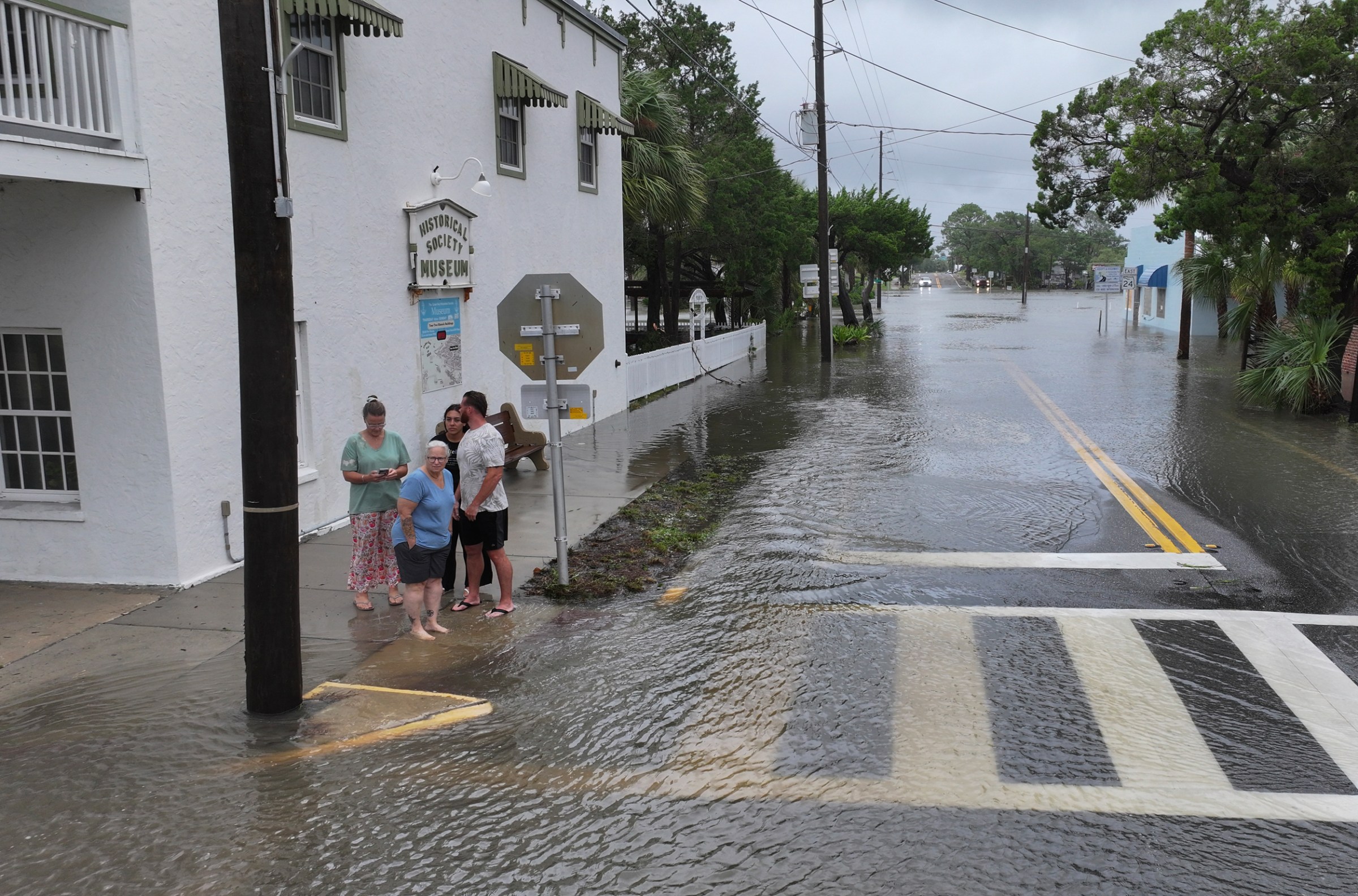 People look out onto a flooded street caused by the rain and storm surge from Stropical Storm Debby on August 5, 2024, in Cedar Key, Florida.