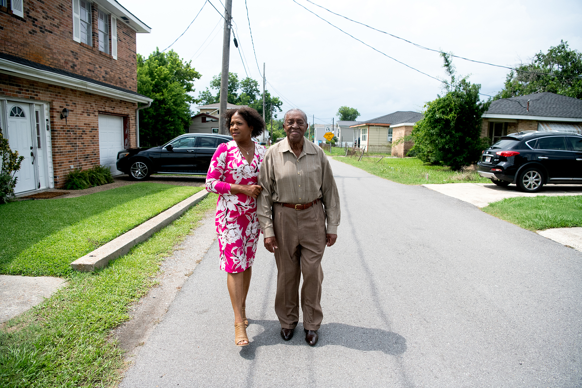 A photo shows a woman in a bright pink floral dress and her father walking through a Louisiana residential neighborhood.