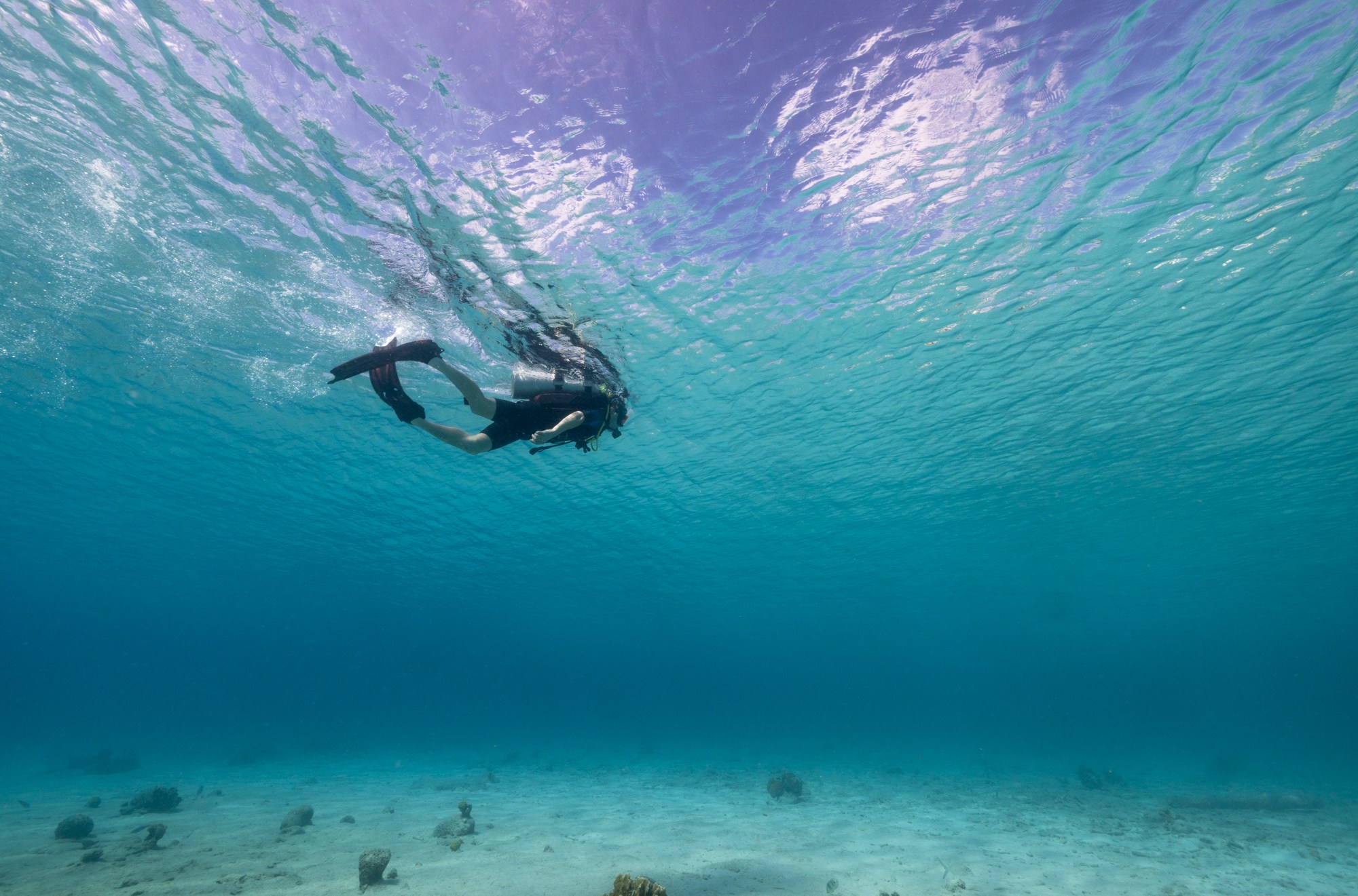 A person in swimming along with surface of water using SCUBA