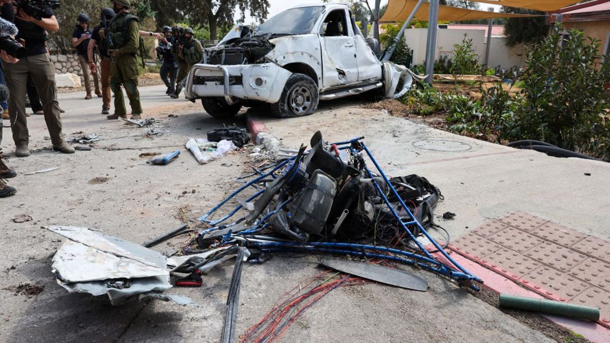 Israeli soldiers and journalists gather around a damaged powered paraglider used by Hamas terrorists in Kfar Aza, south of Israel bordering the Gaza Strip, on Oct. 10, 2023.