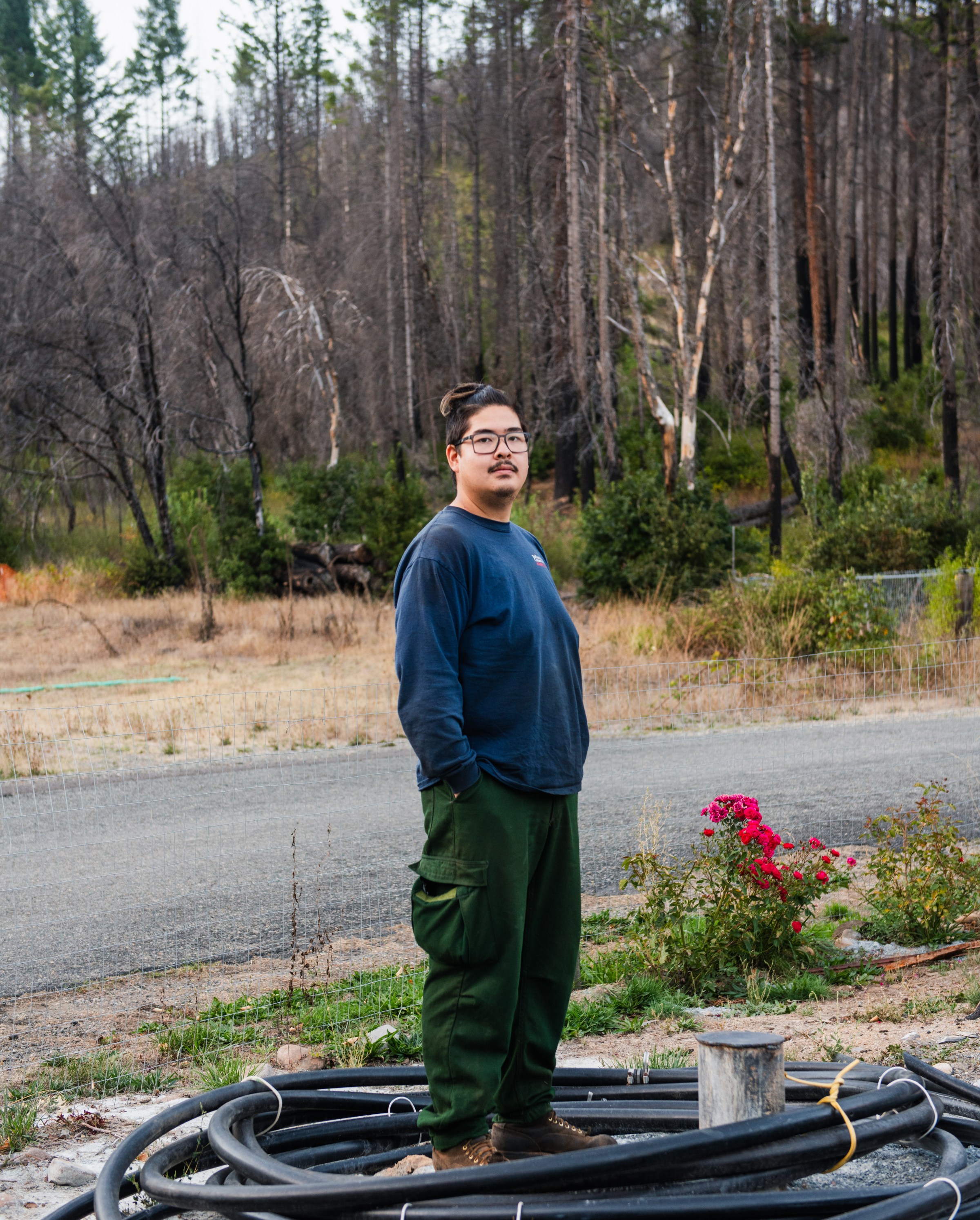 Silas Yamamoto poses for a portrait at the property where his mother and stepfather live in Happy Camp, California. Some of the family’s property and belongings burned during the Slater fire in 2020.