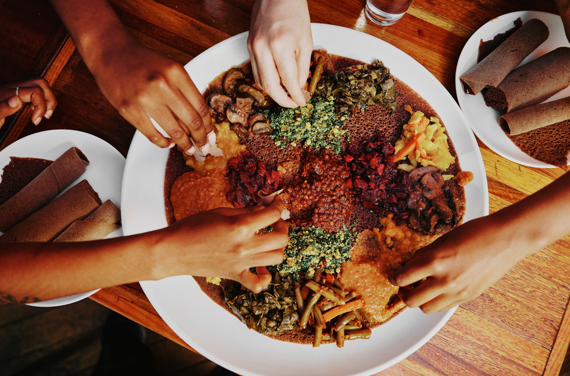 A photo of four hands reaching toward a Beyaynetu spread.