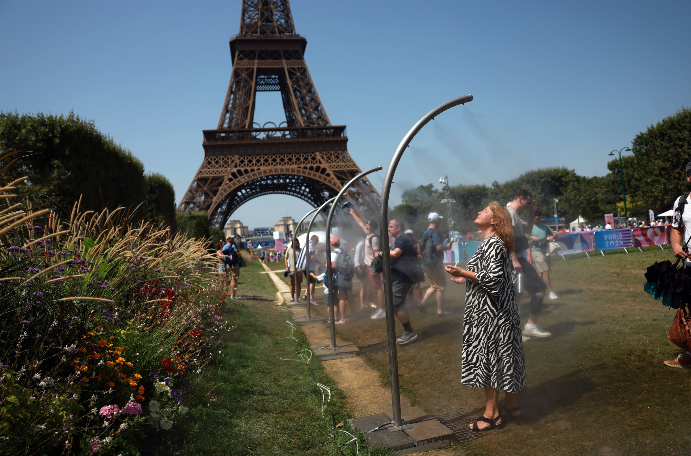 Spectators at the 2024 Olympic Games in Paris cool off at misters in near the Eiffel Tower.