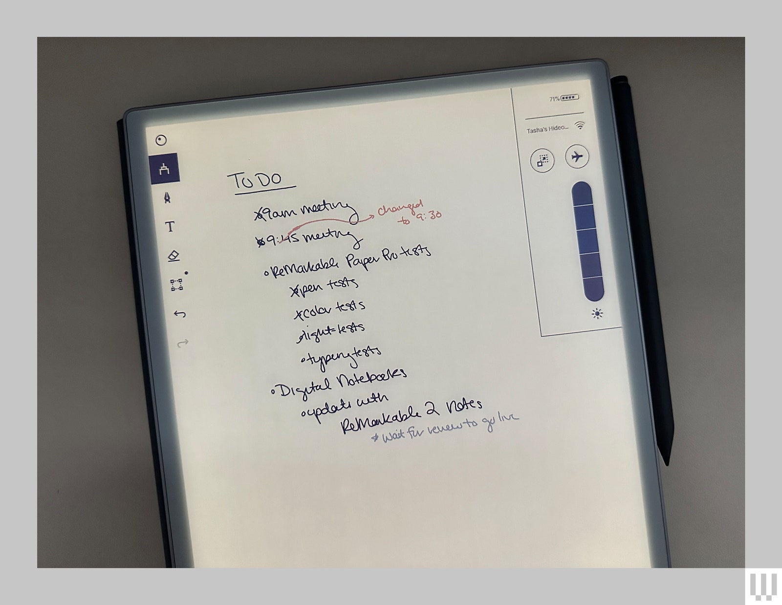 Closeup of the illuminated screen of a digital notebook showing a handwritten todo list. A black stylus is attached to...