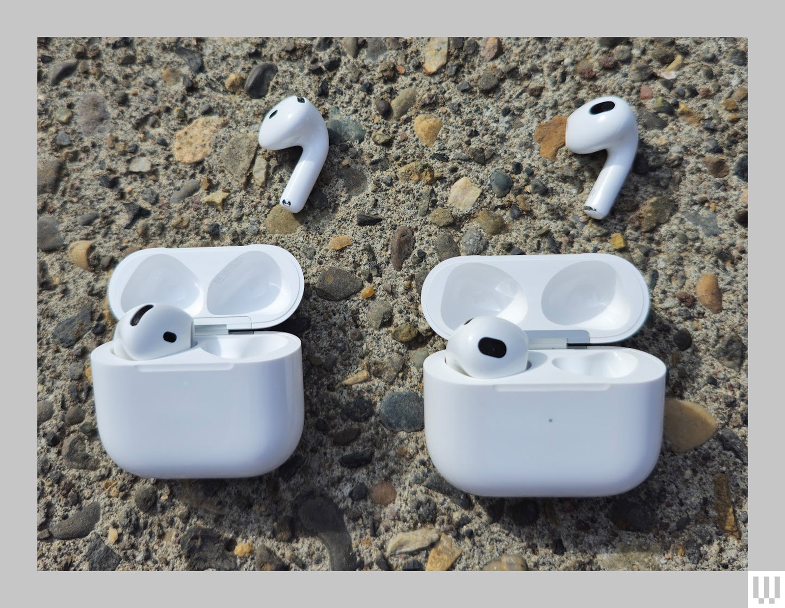 Two small white rounded cases with the lids open each having 1 white earbud inside and 1 white ear bud outside