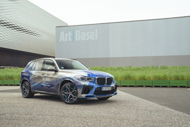 A BMW X5 has been wrapped by an artist and parked in front of a frosted glass building