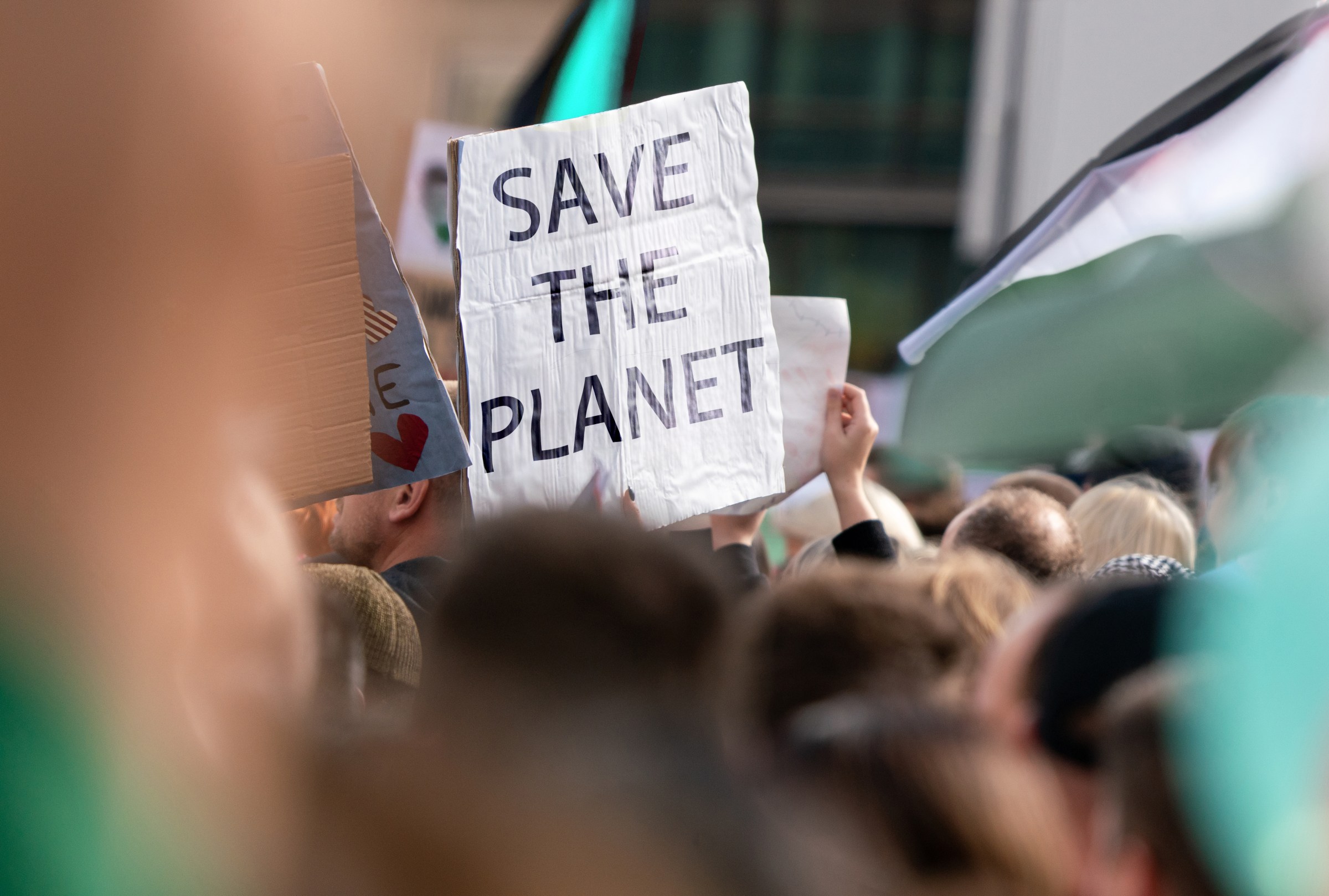 A crowd of climate activists is seen with a prominent Save The Planet sign.