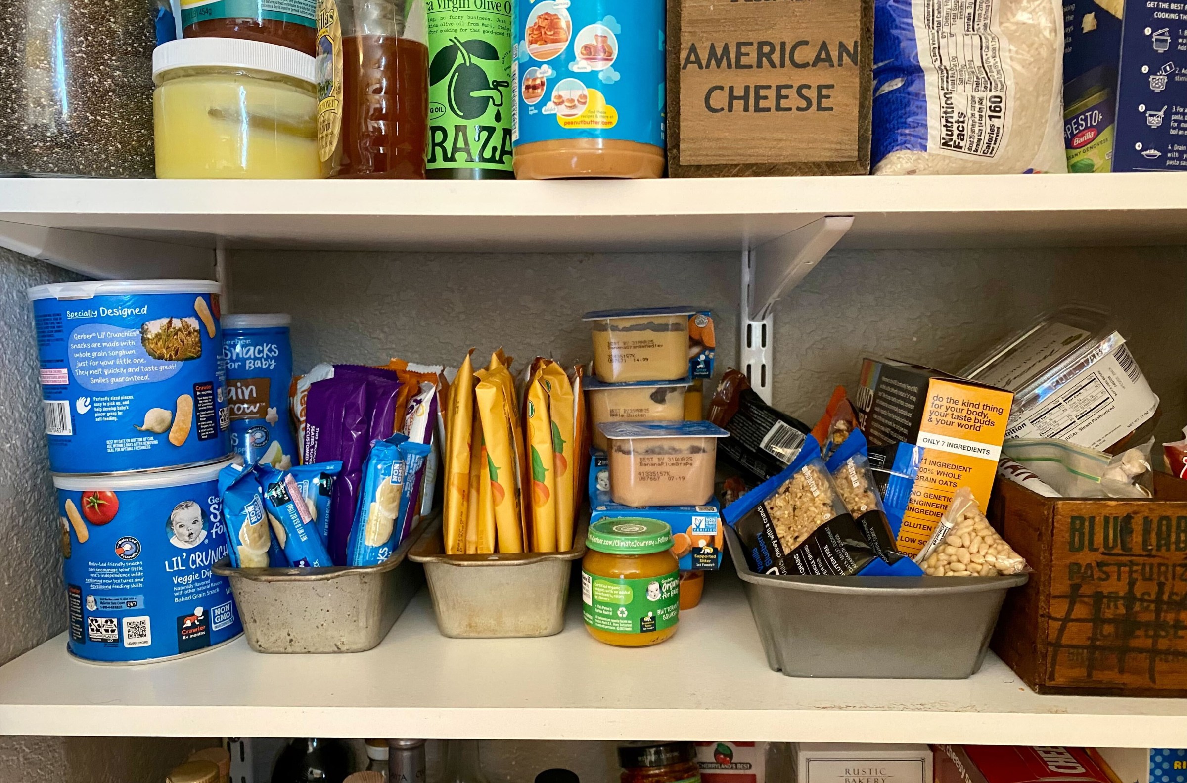 A photo of the author’s pantry, organized but also kind of messy, with bread tins holding baby crackers and granola bars.