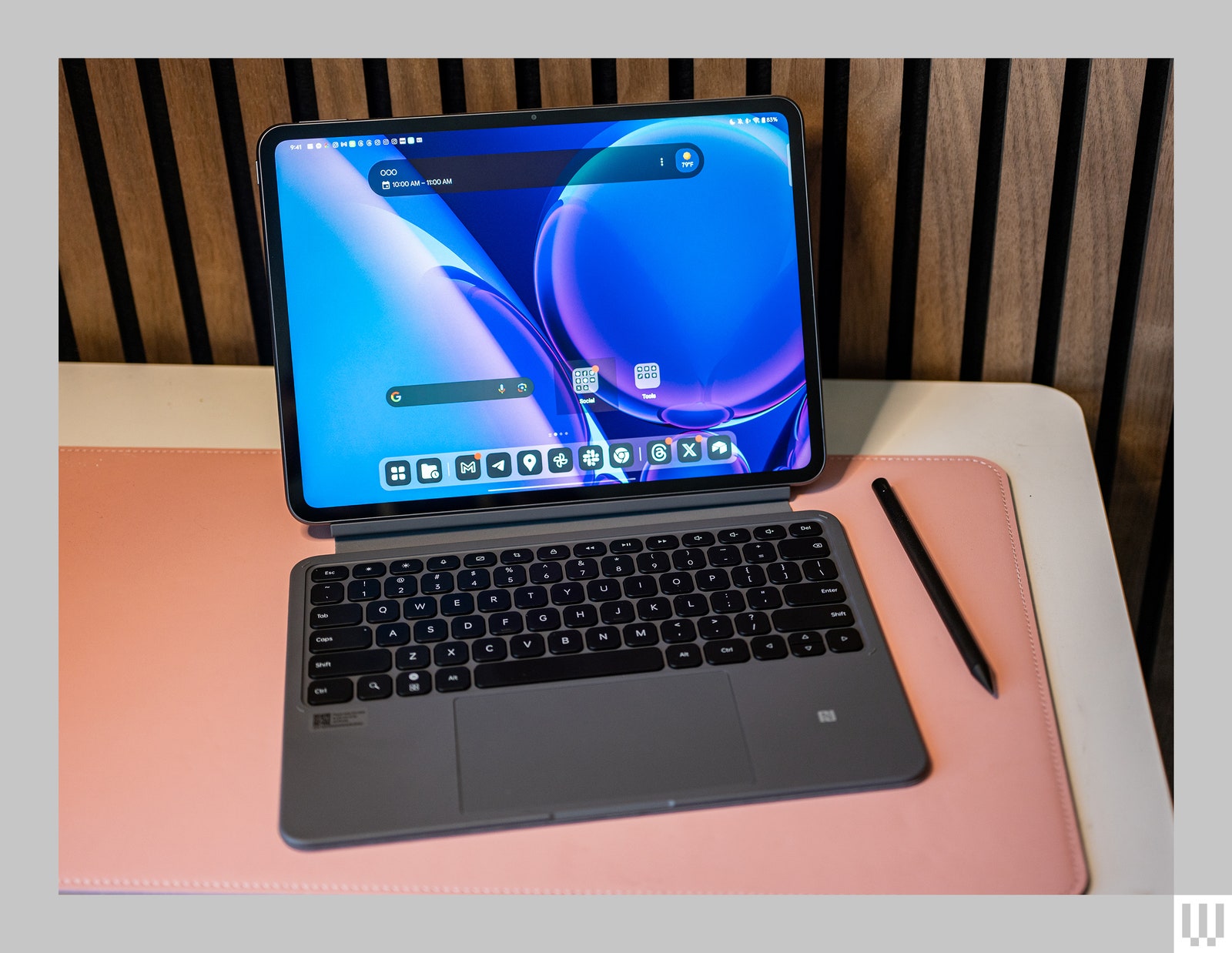 Tablet connected to detachable keyboard sitting on a pink cushioned pad on a desk