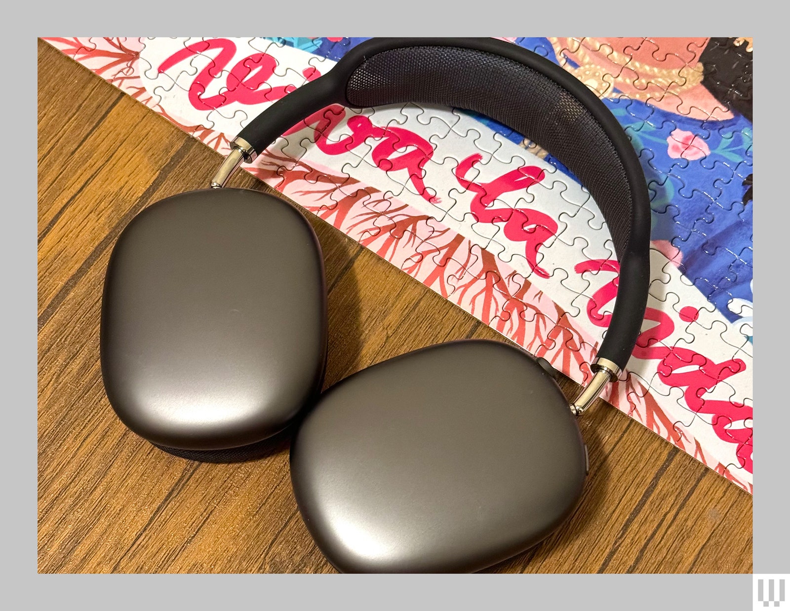 Light grey AirPods Max headphones with black strap placed partially on a puzzle