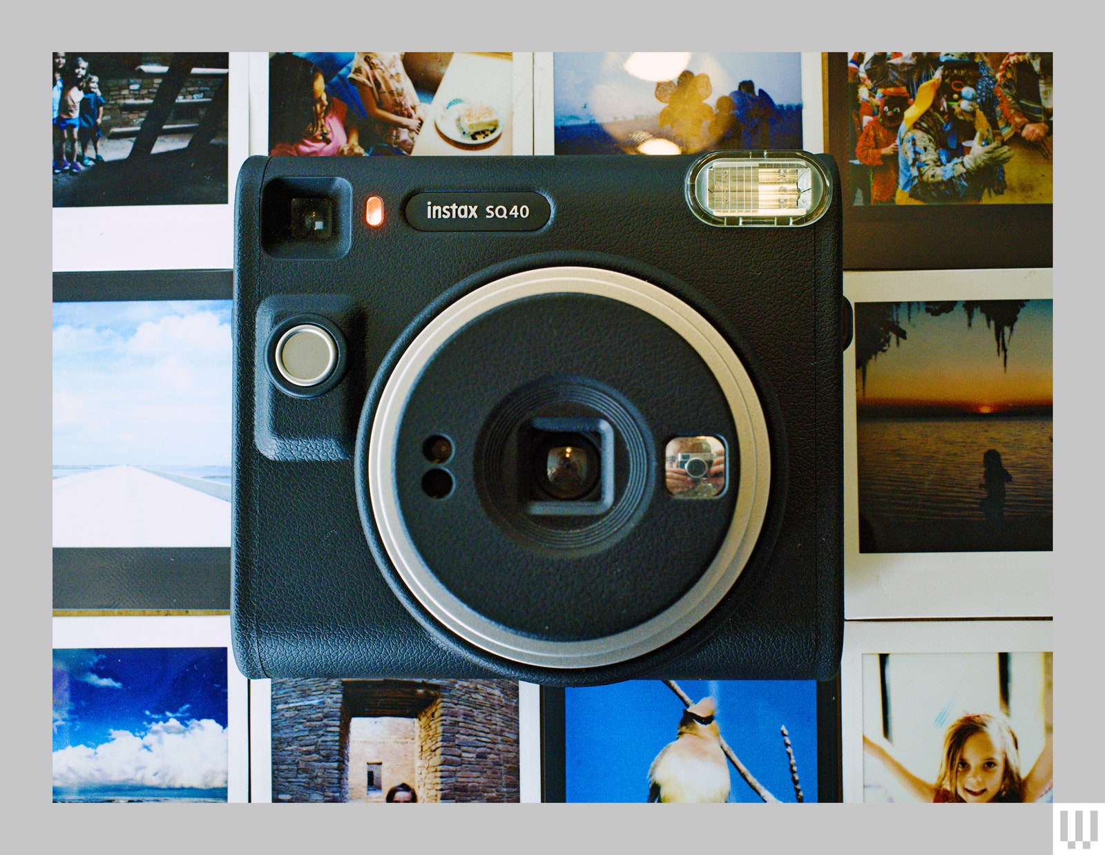 Overhead view of black film camera on top of printed out photos laid out in a grid