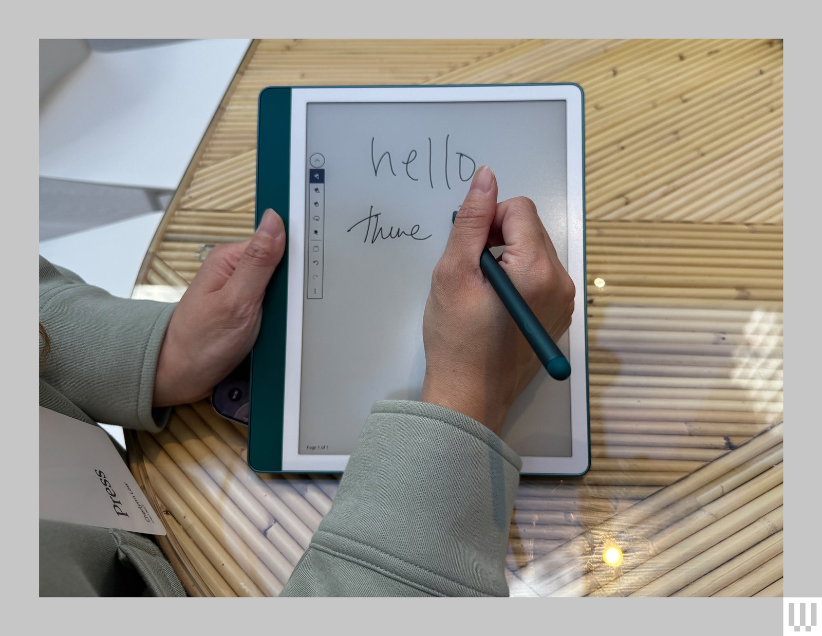 A person using a stylus to scribble on the screen of a Kindle Scribe a teal ereader with interactive screen