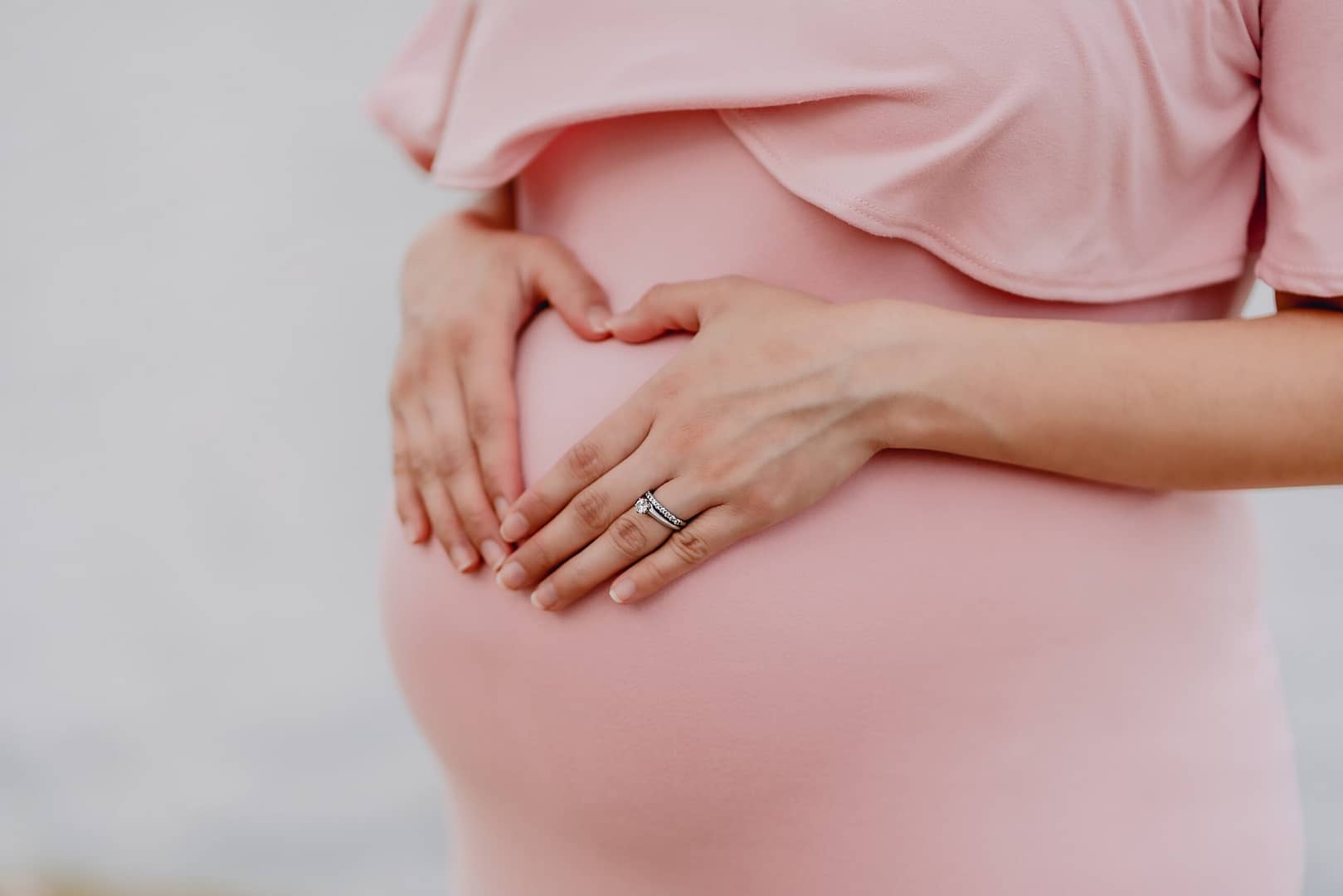 Belly of a pregnant woman forming a heart on her belly