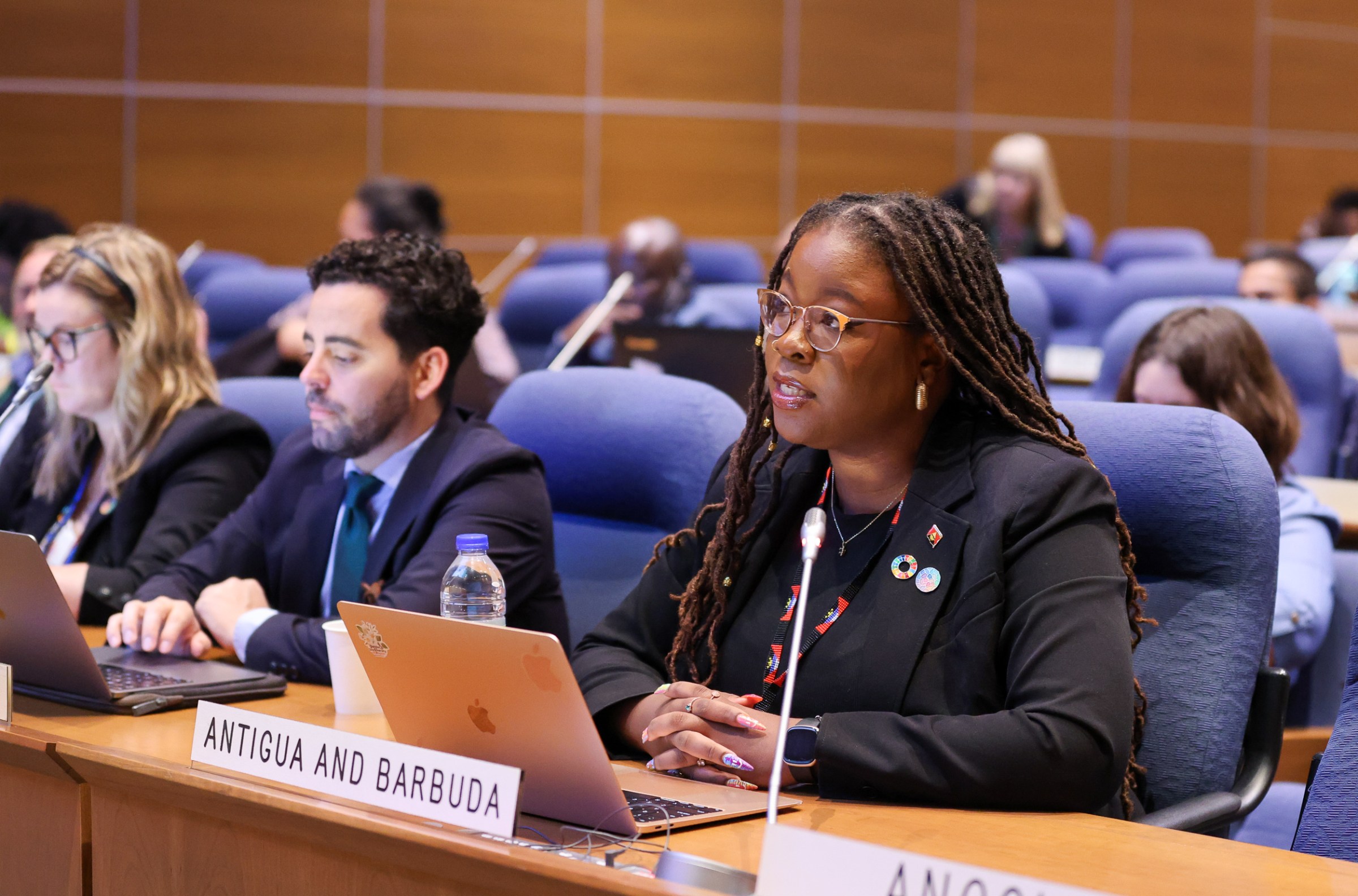 The representative from Antigua and Barbuda sits and listens from her seat and desk.