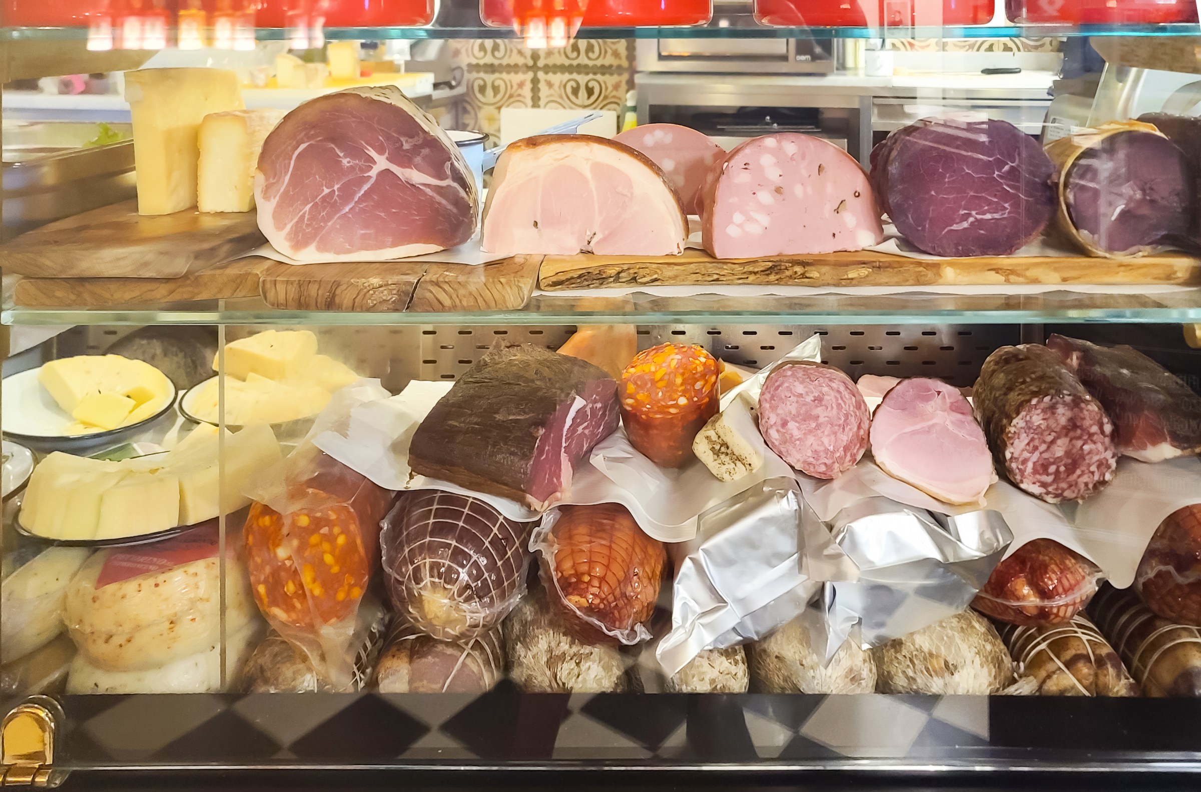 This is a view into a display case at a prosciutteria in Venice, Italy. The case is full of traditional cured meats as well as a selection of cheeses, viewed mostly in cross-section.