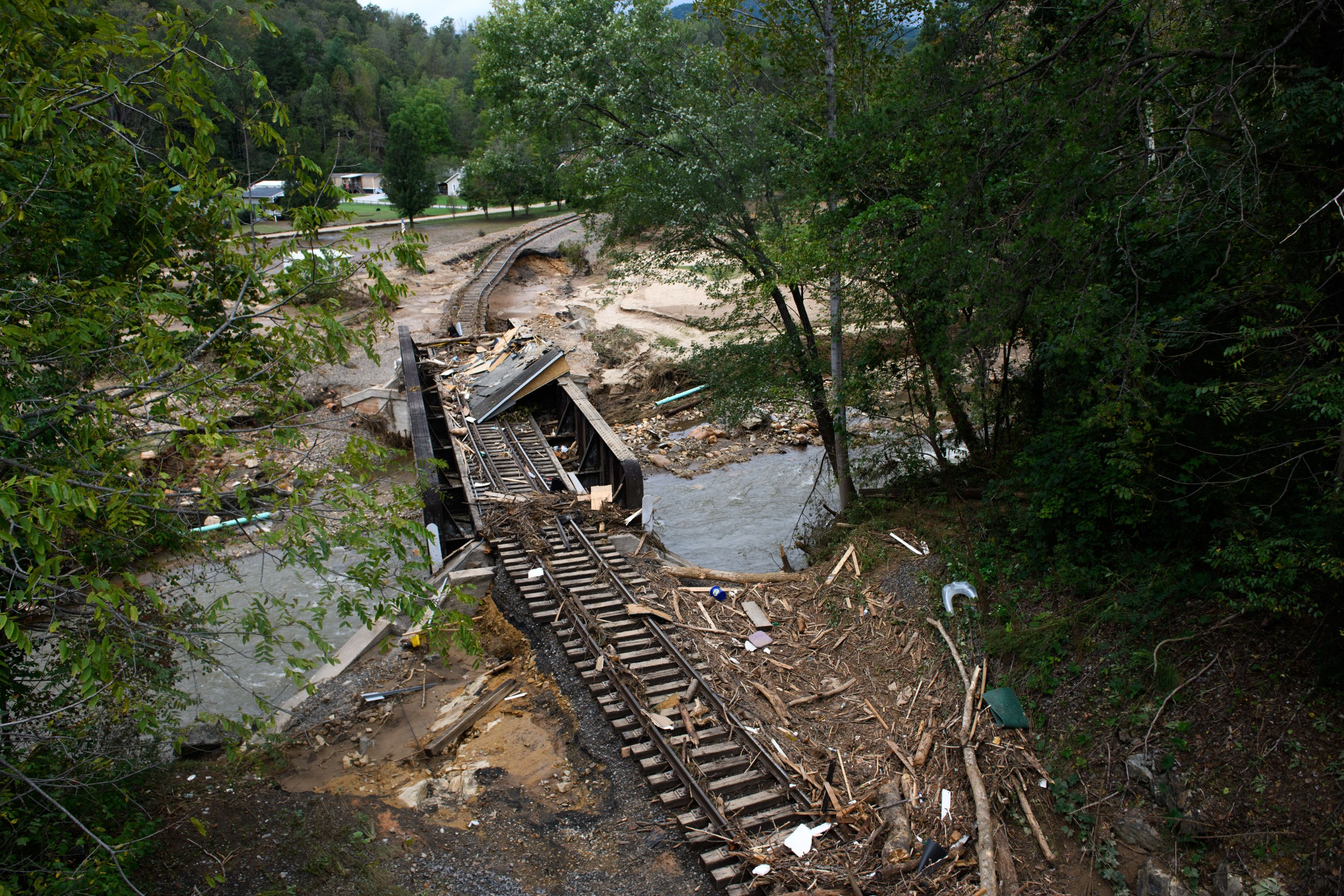 A photo of a railway going over a bride, much of which is destroyed and scattered with debris. 